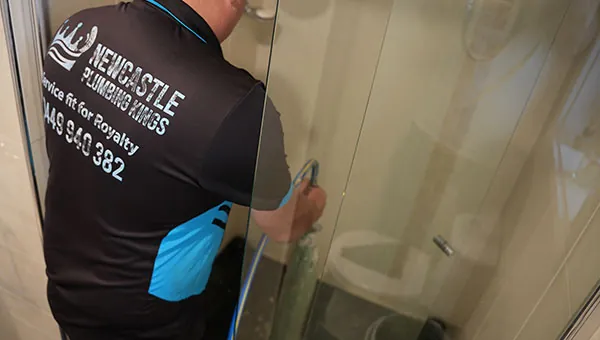 Plumber relining the drain under a shower